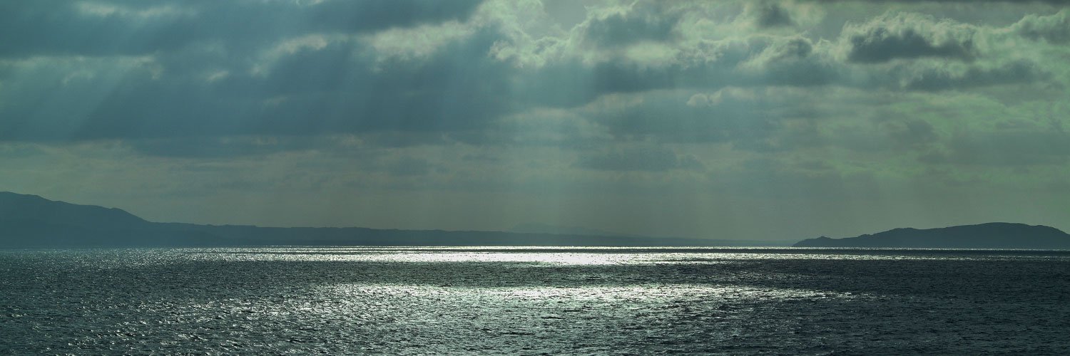 View of the Aegean Sea with dark clouds and sunbeams.