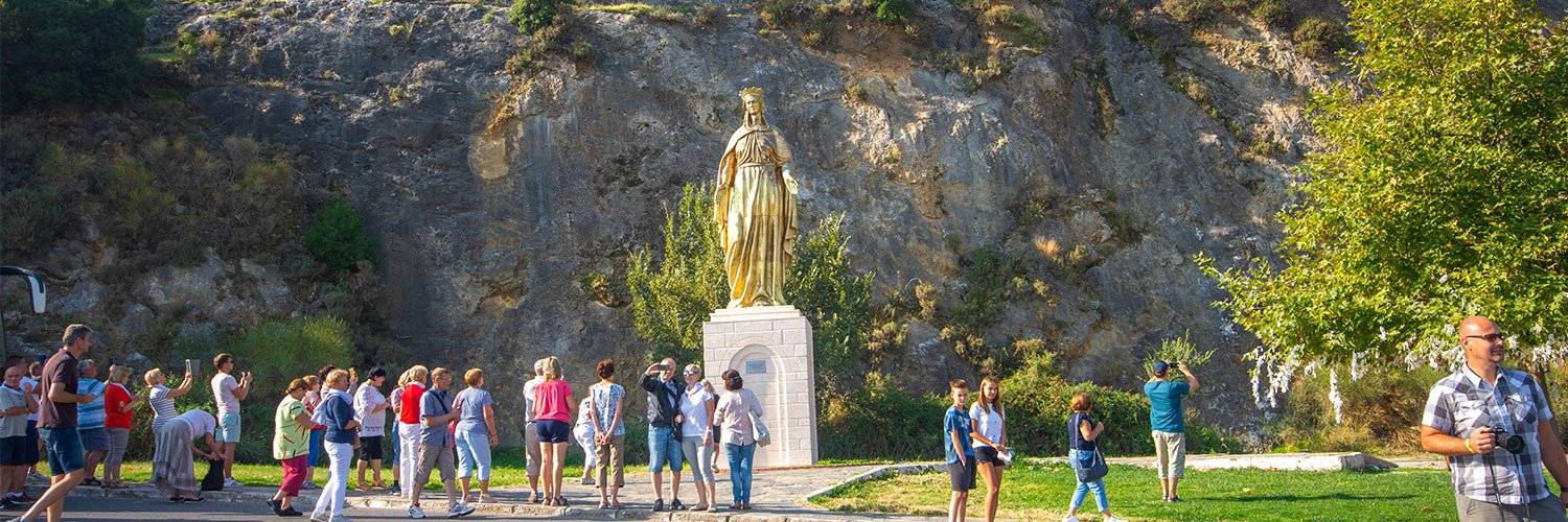 A statue of Virgin Mary in Selcuk towering about 6-7 meters high, with tourists taking photos around it.