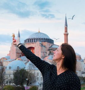A woman feeding birds in front of the historic Hagia Sophia in Istanbul, showcasing a blend of Turkish history and culture.