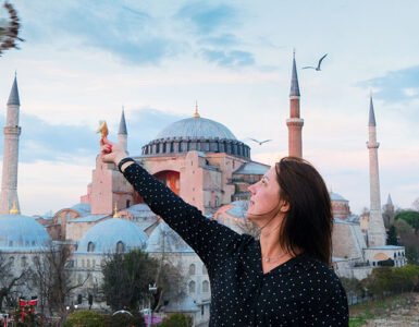 A woman feeding birds in front of the historic Hagia Sophia in Istanbul, showcasing a blend of Turkish history and culture.