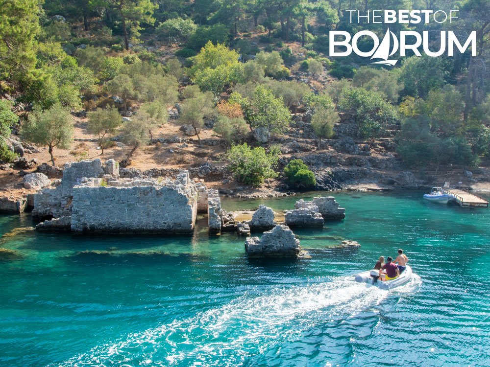 Small boat approaching the ruins of Cleopatra Bath Cove, a peaceful stop often visited during blue cruises along the Aegean coast.