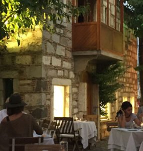 Guests enjoying a sunset dinner at a cosy Bodrum restaurant under leafy trees.